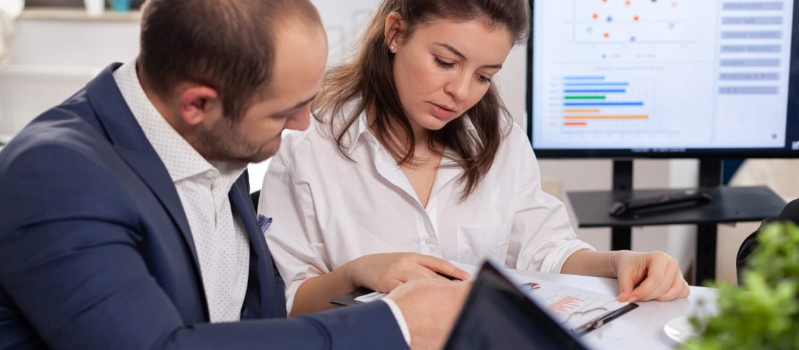 Colleagues of startup business discussing looking at documents in company board brainstorming conference room checking graphs and charts. Financial analysis during briefing.